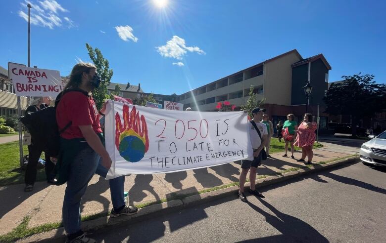 Protesters hold signs.