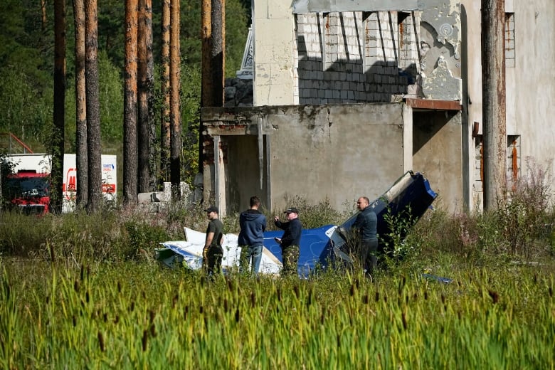 Russian soldiers look at a portion of wreckage from a plane that crashed near the village of Kuzhenkino on Wednesday.