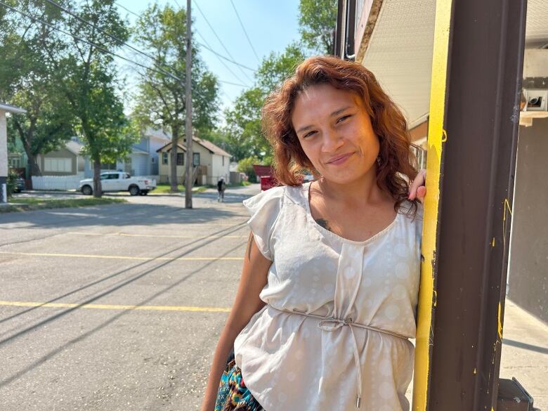 A young Indigenous mother poses in the sun outside a rundown motel. 