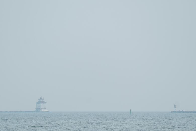 The bottom of the photo shows blue Lake Superior waters and beyond that a lighthouse. The lighthouse and sky are hazy because of forest fire smoke, so you can't see the Sleeping Giant.