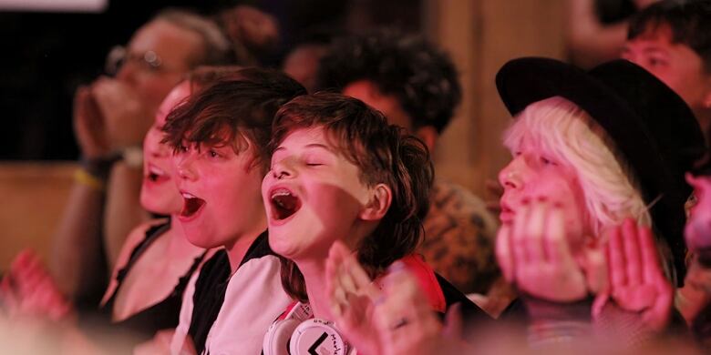 Still frame from the film Summer Qamp. Queer children enthusiastically singing together.