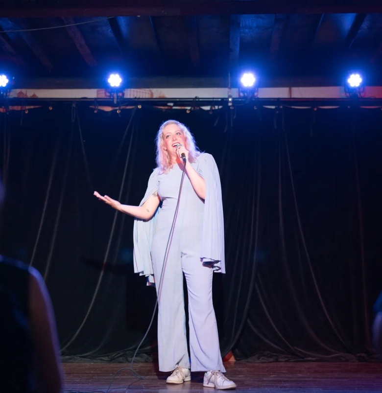 A woman speaking into a microphone onstage. 