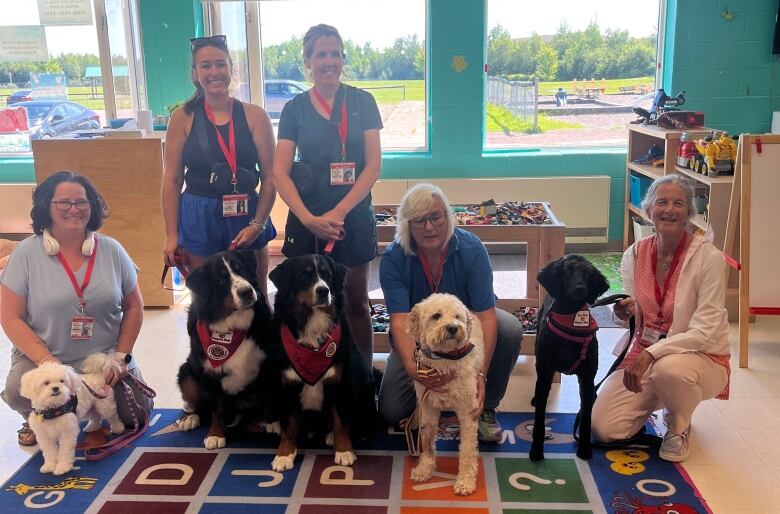 Group of people standing with dogs sitting in front of them.