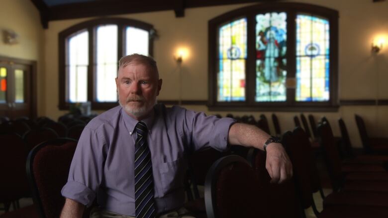 A pastor sits in a church. 