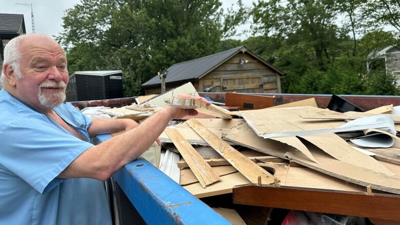 70-year-old Watford, Ont. resident Gary Tait shows off the dumpster full of scrapped material from his now torn-up basement, where 14 inches of water pooled during Wednesday's rainstorm in Middlesex and Lambton Counties. 