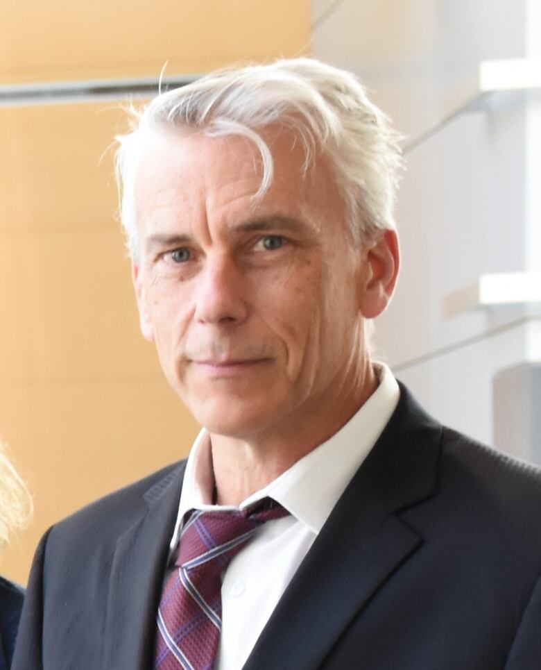 A man with white hair smiles into the camera. 