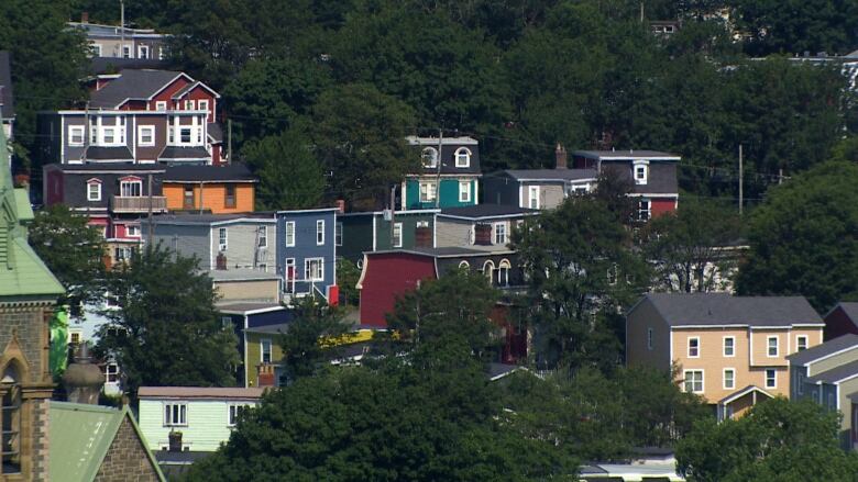 A view overlooking a group of colourful houses surrounded by green trees. 