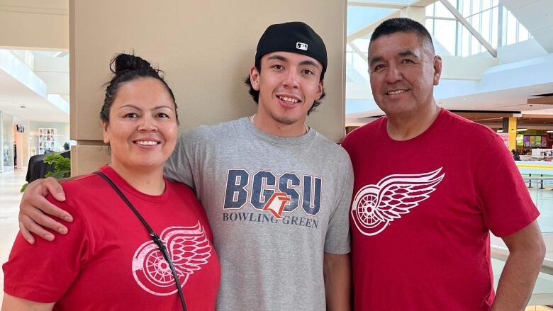 A Cree family stands in Detroit Red Wings red tee shirts smiling at the camera.