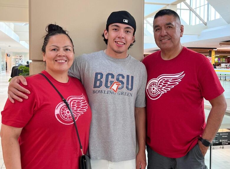 A Cree family stands in Detroit Red Wings red tee shirts smiling at the camera.