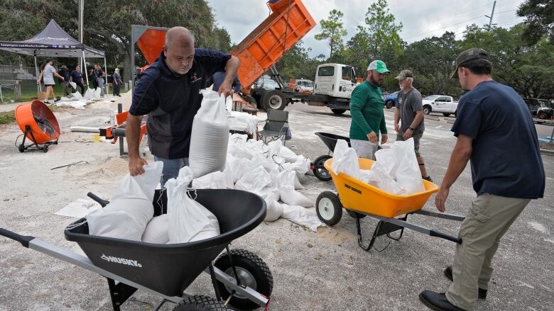 people filling sandbags and putting them into wheel barrows