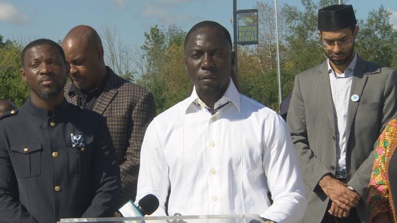 A man stands at a podium with others behind him.