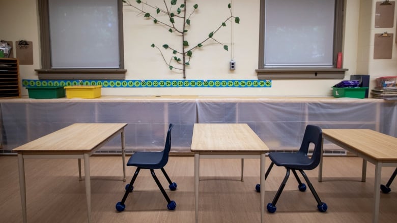 A kindergarten classroom with empty tables and chairs.