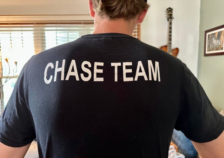 A man wearing a T-shirt promoting his storm-chaser group.