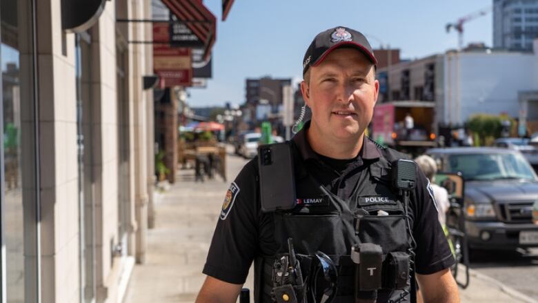 A police officer stands on a city street on a sunny summer day.