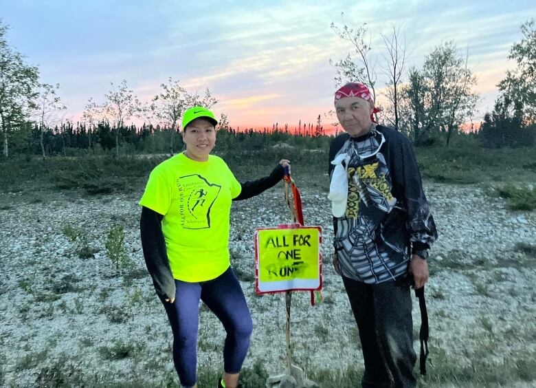 Nelson and Tamara stand in front of a sunset holding a sign promoting their run for diabetes awareness. 