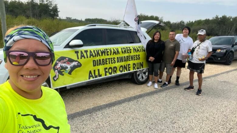 Tamara takes a selfie with other runners and walkers next to her car decorated for the awareness run. 