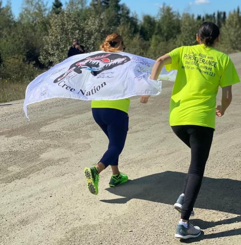 Tamara and another person run away from the camera holding a flag promoting diabetes awareness.