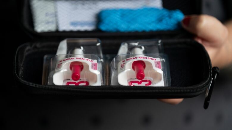 A woman holds a naloxone kit in her hands.