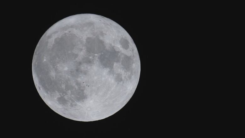 Three Canada geese are vaguely visible flying in front of the super blue moon, from Windsor, Ont., Aug. 30, 2023.