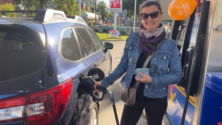 a woman pumps gas into her car.