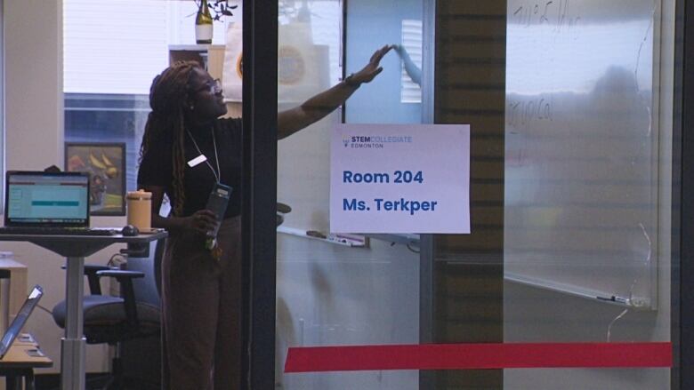 A woman points to a whiteboard in a classroom.