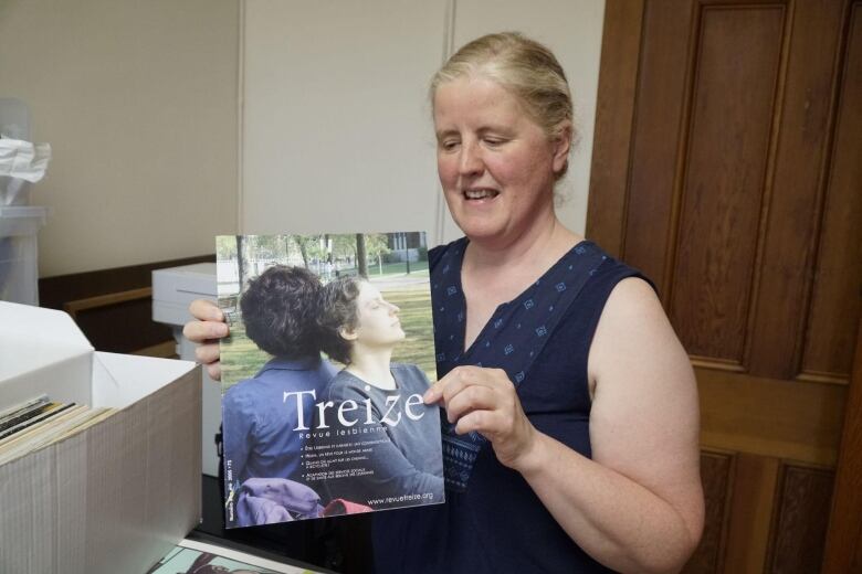 Blonde woman holding up a magazine called Treize