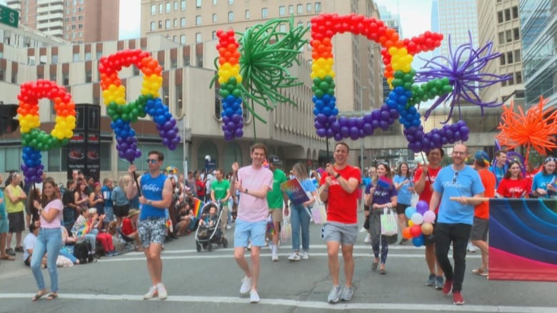 A group of people holding balloons in the shape of the word Pride