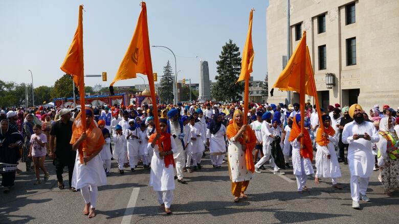 A crowd of people walk down a street. 