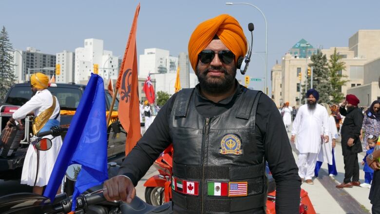 A man wearing sunglasses holds the handle of a motorcycle.