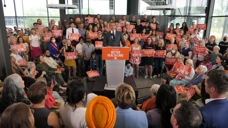 Man stands amidst orange crush supporters.