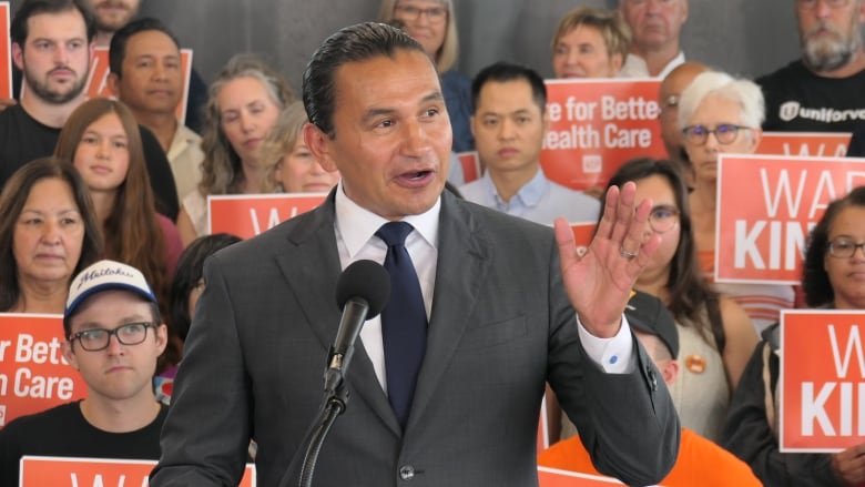 A man in a suit and tie speaks into a microphone.