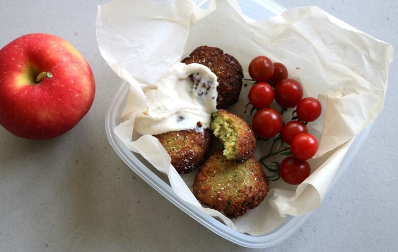 Falafel in a lunchbox along with fruits.