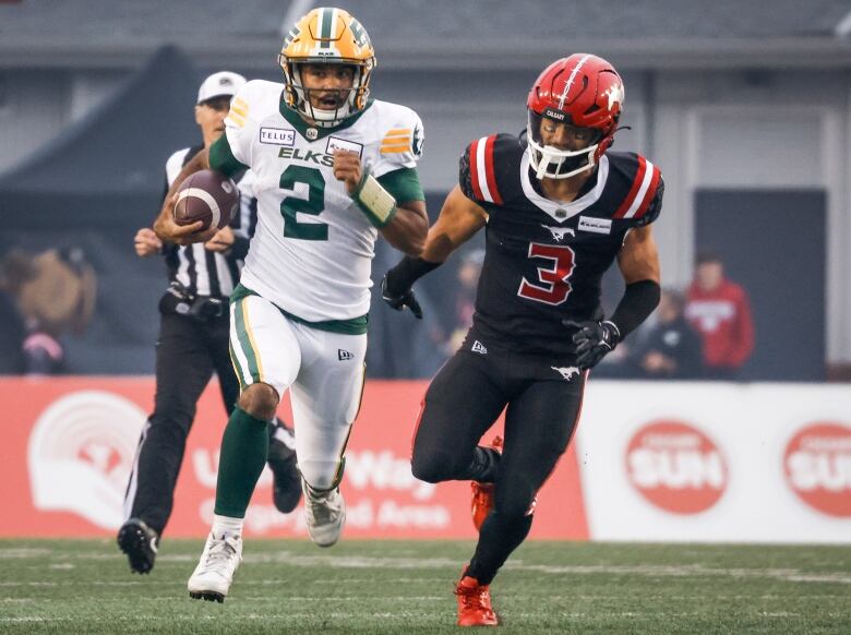 Two football players running down a field. 