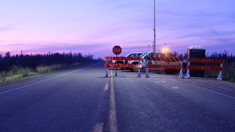 Purple skies illuminate a barricade across a road.