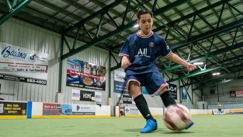 A young boy kicks a soccer phone.