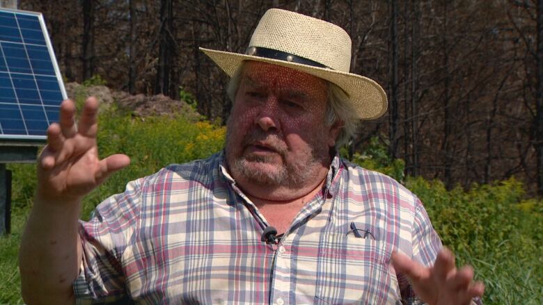 A man in a white brimmed hat is sitting outside.