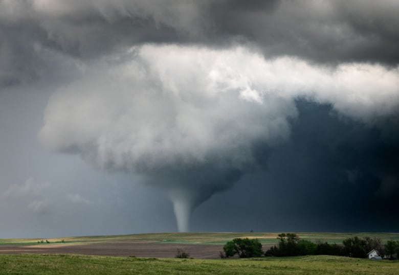 A large tornado touches down in front of farmer's fields.