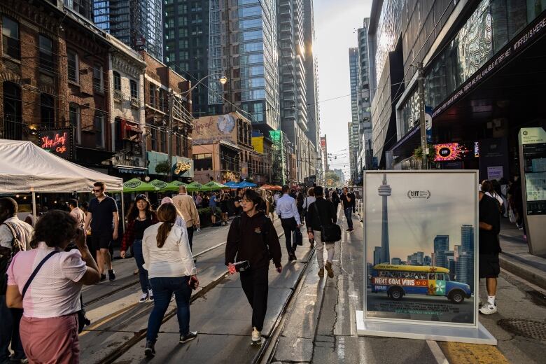 People walk down the middle of the street in front of the main TIFF theatre