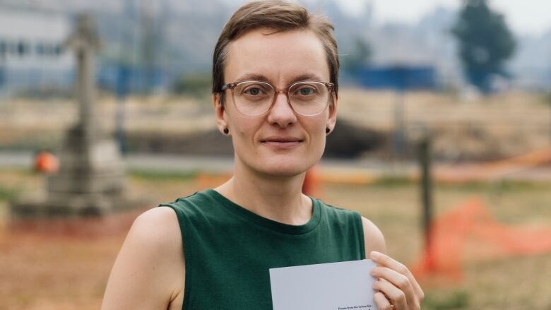 A woman wearing a green dress poses with a book in her hands.