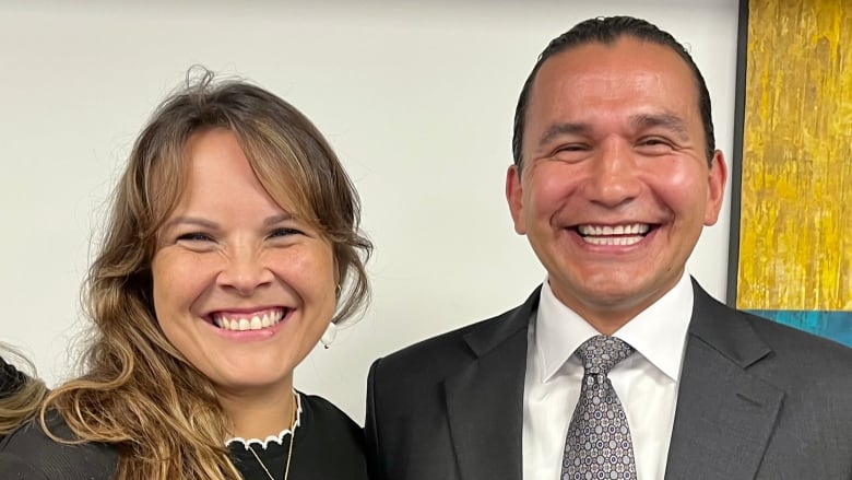 A woman and a man smile and pose for a photo together.