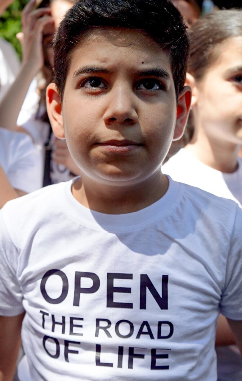 An Armenian child wears a shirt that says 'Open the Road of Life.'