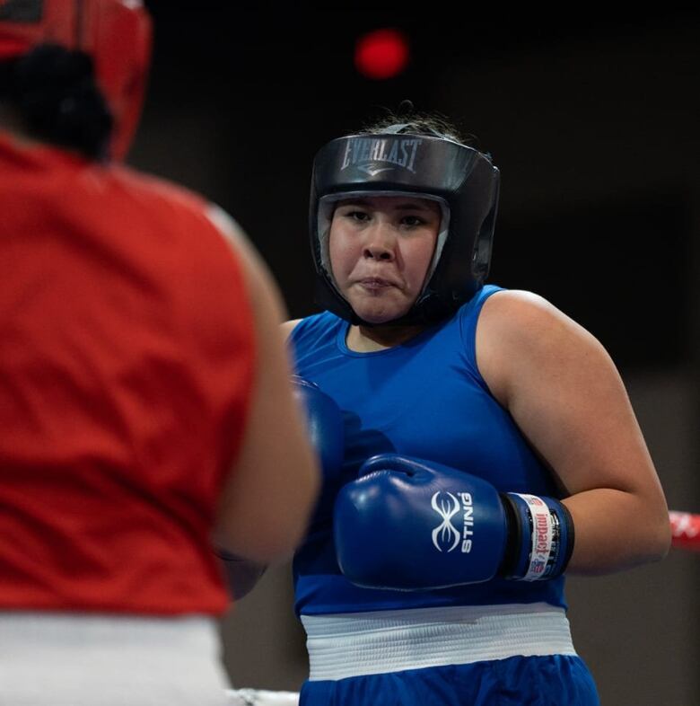 A young boxer in blue eyes her opponent 