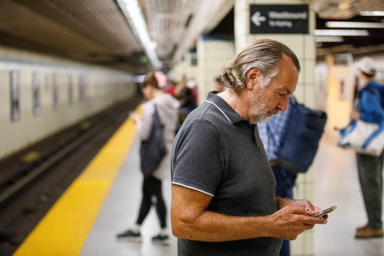 Commuters are photographed on their phones at Yonge Station in Toronto, on Aug. 23, 2023.