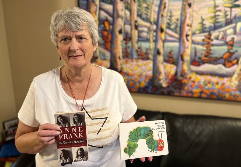 Woman holding a copy of the Diary of Anne Frank and the Very Hungry Catepillar.