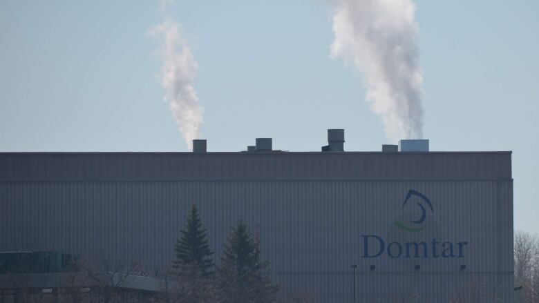 A large grey building with the words 'Domtar' with smokestacks out the top 