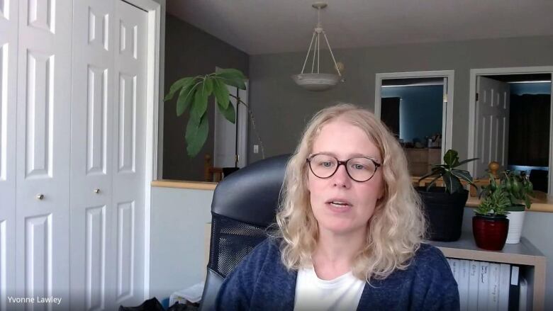 Yvonne Lawley participates in an interview over Google Meet. She wears black, round glasses, a blue sweater and has curly blonde hair.