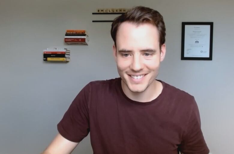 A man in a maroon t-shirt smiles for the camera.