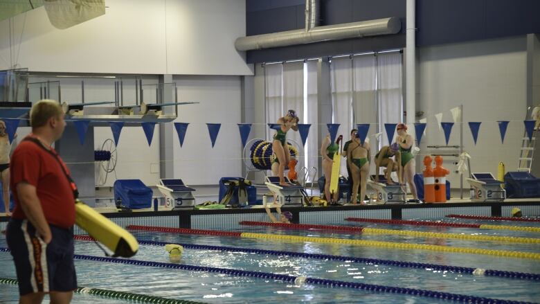 A lifeguard watches as swimmers work in the pool