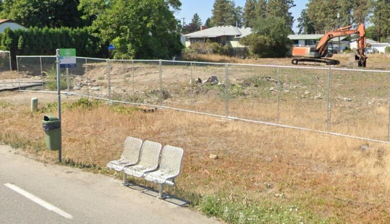 A bus stop in a suburban community, with an empty lot behind it.