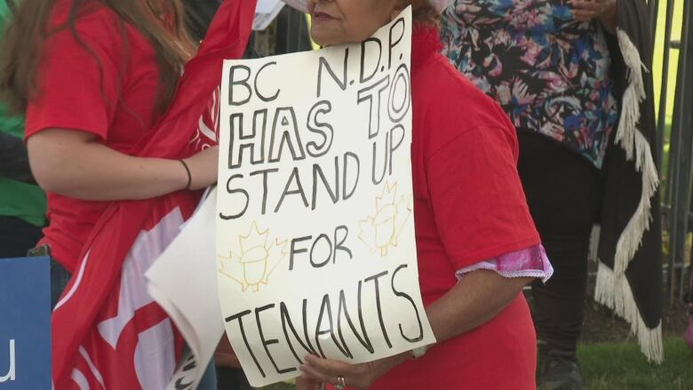 A person holds a sign that reads B.C. NDP has to stand up for tenants.